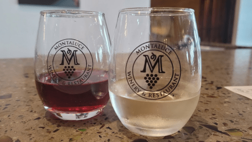 Two wine glasses with the Montaluce Winery & Restaurant logo, one filled with red wine and the other with white wine.
