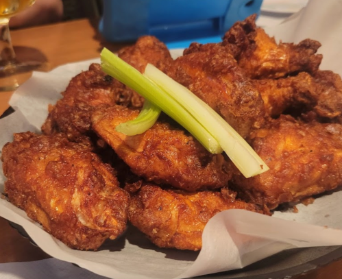A plate of crispy fried chicken wings garnished with a slice of green celery.