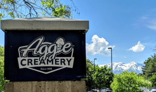 Sign for Aggie Creamery with mountains and blue sky in the background. Established in 1888.