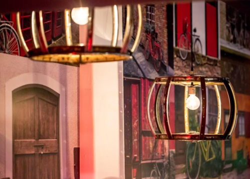 Two decorative light fixtures hang against a colorful wall featuring bicycles and doors.