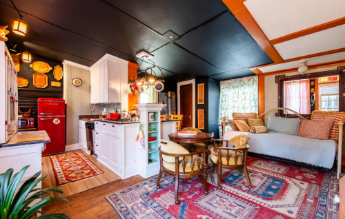 Cozy kitchen and living area with vintage decor, colorful rugs, and a mix of modern and retro furnishings.