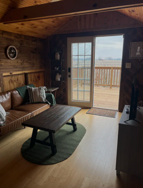 Cozy living room with a leather sofa, wooden accents, and a view of a deck through glass doors.