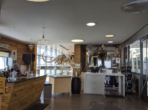 Interior of a visitor center in Wyoming featuring a mammoth skeleton, reception desk, and informational displays.