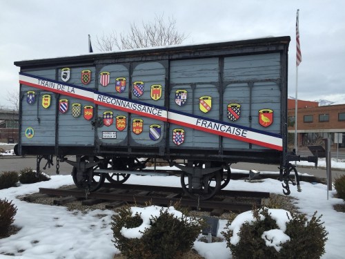 A blue train car with various coats of arms displayed on its side, set against a snowy landscape.