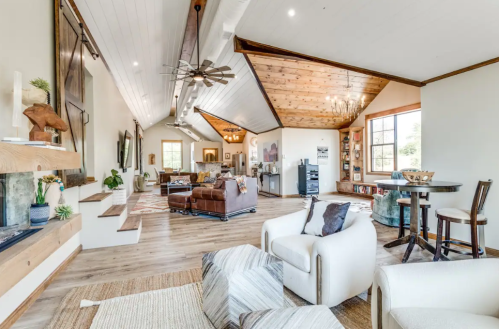 Spacious living room with high ceilings, wooden accents, and cozy seating areas, featuring a mix of modern and rustic decor.