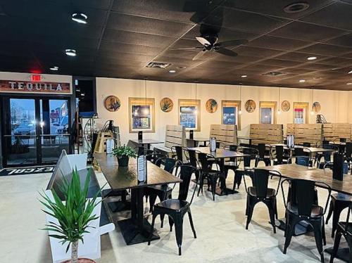 Interior of a restaurant featuring wooden tables, black chairs, and decorative wall art, with a door labeled "Tequila."