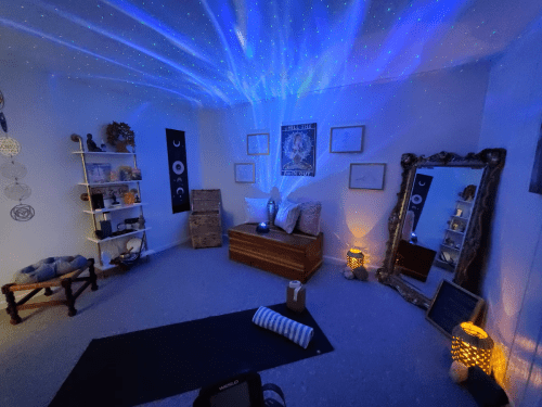 A cozy room with blue starry lights, a wooden bench, yoga mat, and decorative shelves, creating a calming atmosphere.