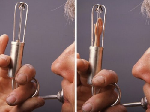 A metal device with a small hand inside, held near a person's face, showcasing a whimsical or surreal concept.