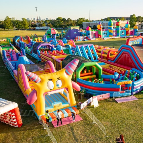 A colorful inflatable amusement park with various slides and obstacle courses set up in a grassy area.