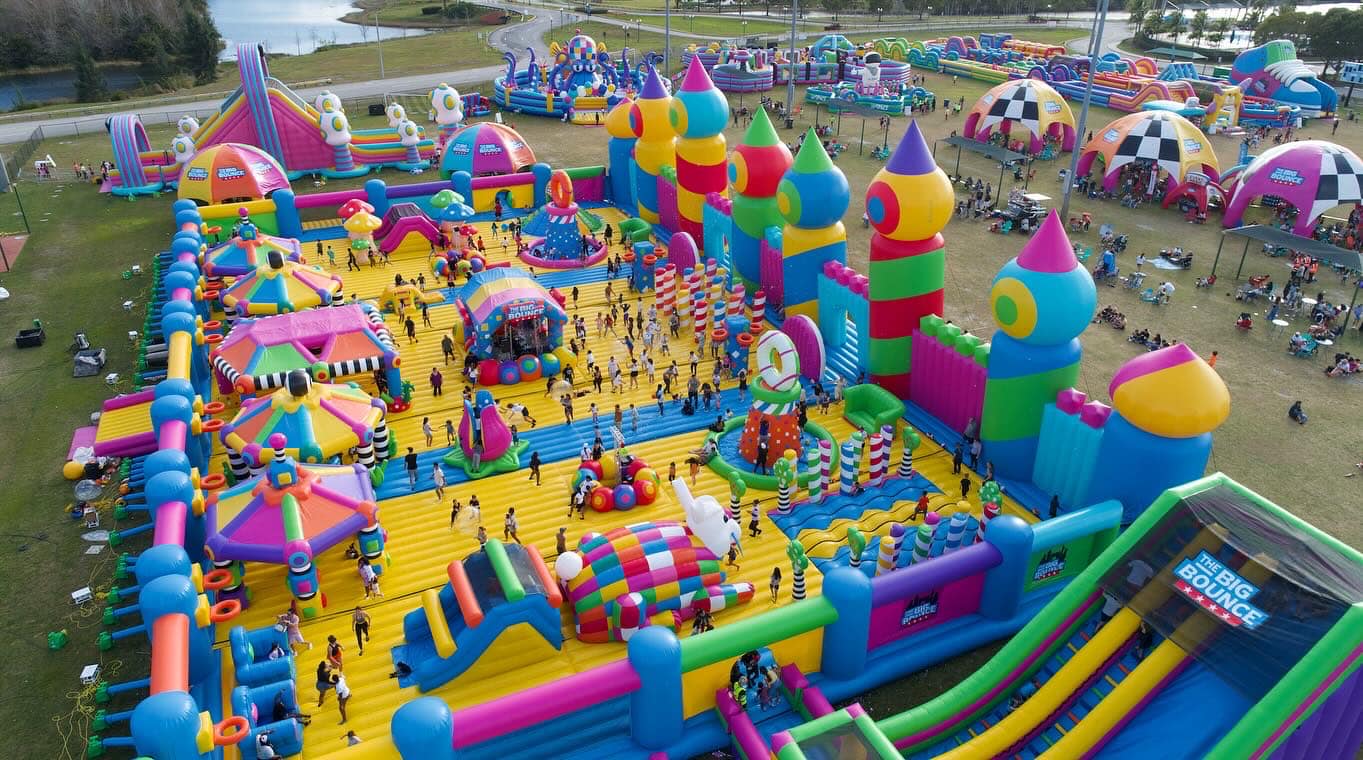 Kids playing on colorful bounce houses at an outdoor community event