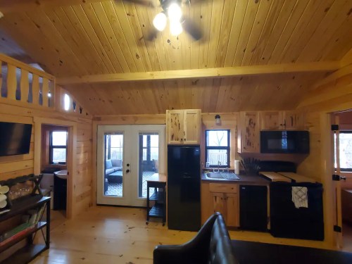 Cozy wooden cabin interior featuring a kitchen, dining area, and large windows with natural light.