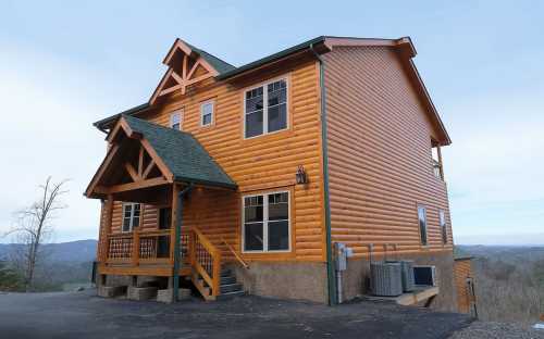 A large log cabin with a steep roof, wooden accents, and a scenic view in the background.