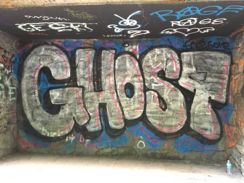 Graffiti on a wall featuring the word "GHOST" in large, stylized letters with colorful accents.