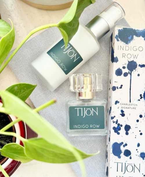 A bottle and spray of Tijon Indigo Row fragrance beside a plant and its packaging on a light surface.