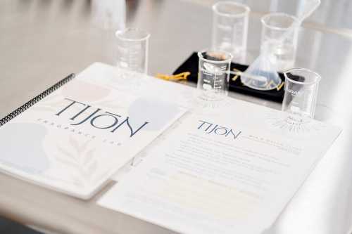 A table with fragrance lab materials, including beakers, a funnel, and informational brochures about Tijon.