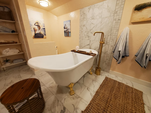 A stylish bathroom featuring a freestanding tub, gold fixtures, and decorative artwork on the walls.