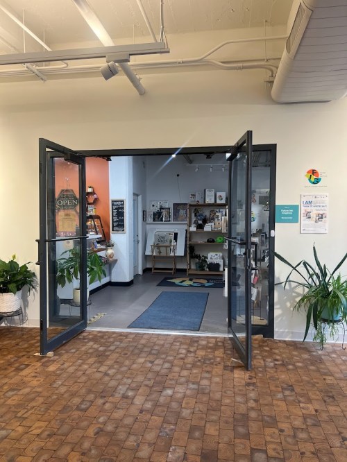Open double doors leading into a bright, welcoming space with plants and shelves filled with various items.