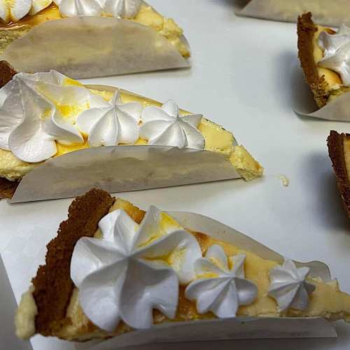 Slices of dessert with creamy filling, topped with white whipped cream, on a white plate.