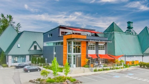 Exterior view of DeLille Cellars, featuring modern architecture and a landscaped parking area under a blue sky.