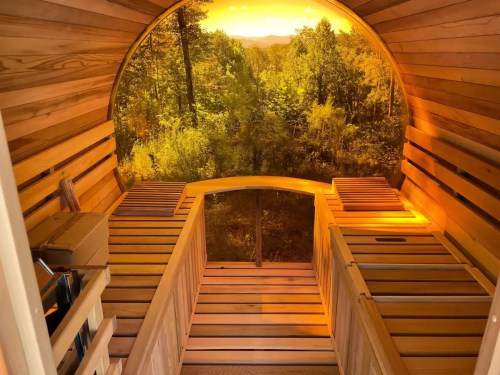 Interior of a wooden sauna with benches, featuring a large window showcasing a scenic forest view.
