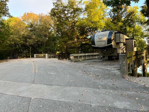 A parked RV on a wooden bridge surrounded by trees in a serene outdoor setting.