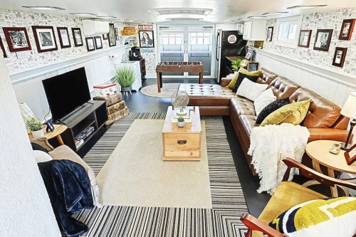Cozy living space with a leather sofa, coffee table, TV, and decor, featuring a foosball table and patterned walls.
