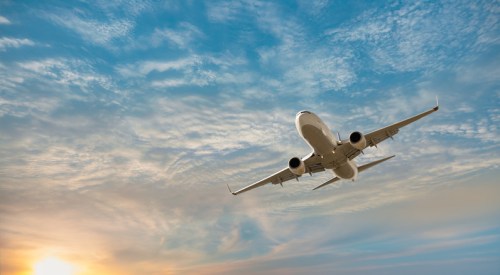 An airplane takes off against a vibrant sunset and cloudy sky.