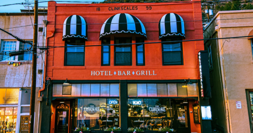 A colorful building with striped awnings, featuring "Hotel Bar Grill" signage, in a lively street setting.