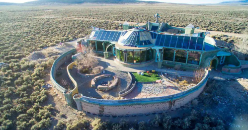 Aerial view of a unique, modern home surrounded by desert landscape and greenery.
