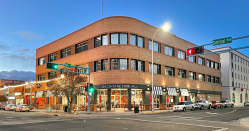 A brick building with large windows, featuring a food hall, at the corner of Central Ave and 505 Central Food Hall.