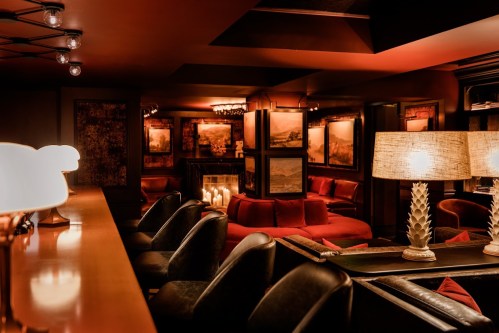 Cozy lounge with dim lighting, plush seating, and framed artwork, creating an inviting atmosphere.