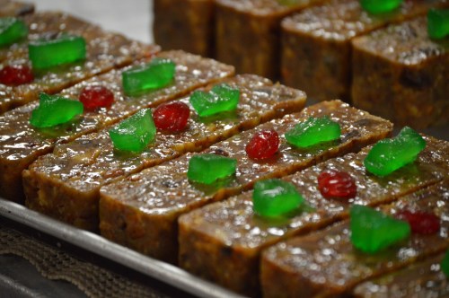 A close-up of sweet, layered dessert bars topped with green and red jelly candies.