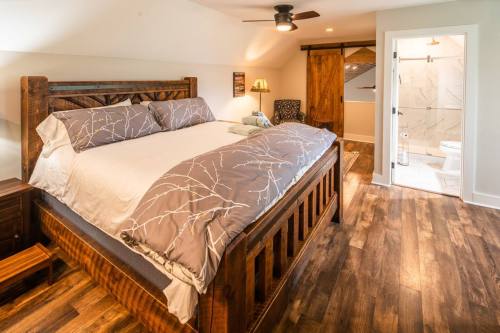 Cozy bedroom featuring a wooden bed, soft bedding, and a modern bathroom with a glass shower. Warm wood floors.