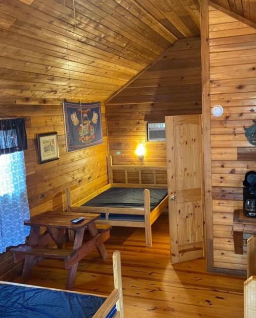 Cozy wooden cabin interior with two beds, a picnic table, and a warm, rustic atmosphere.