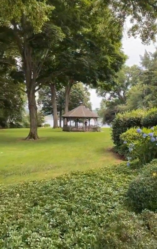 A serene park scene featuring a gazebo surrounded by lush greenery and trees.