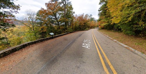 A scenic view of a winding road surrounded by colorful autumn trees in a rural area.