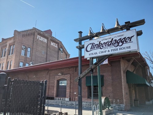 Sign for Clinkerdagger restaurant in front of a historic flour mill building on a sunny day.