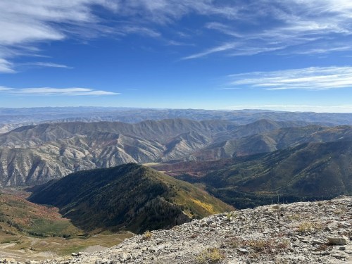 A panoramic view of mountains with colorful autumn foliage under a clear blue sky.
