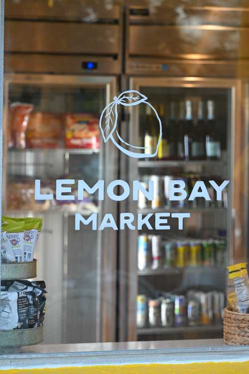 A storefront window displaying the "Lemon Bay Market" logo with shelves of products visible inside.