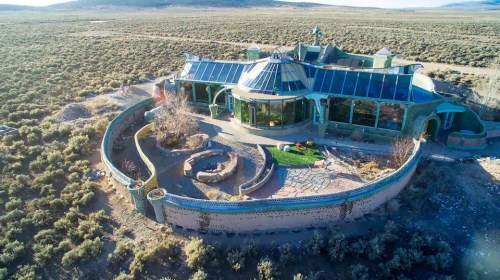 Aerial view of a unique, modern home surrounded by desert landscape and greenery.
