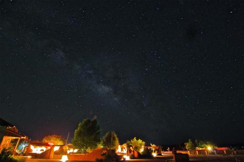 A starry night sky filled with stars and the Milky Way over a desert landscape with illuminated structures.