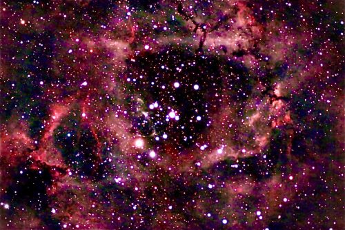 A vibrant cosmic scene filled with colorful nebulae and numerous bright stars against a dark background.