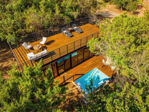 Aerial view of a modern wooden deck with lounge chairs and a small pool, surrounded by greenery.