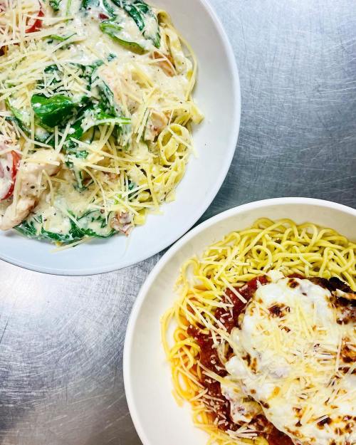 Two bowls of pasta: one with creamy sauce and vegetables, the other with marinara sauce and melted cheese.