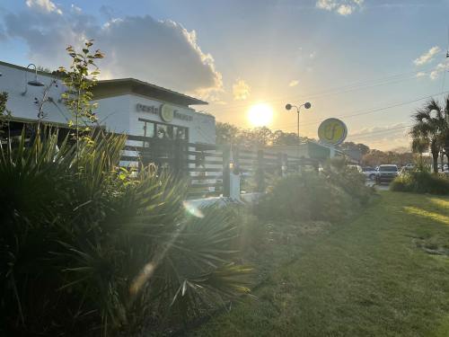 A restaurant exterior at sunset, featuring palm trees and a sign, with a warm glow from the setting sun.