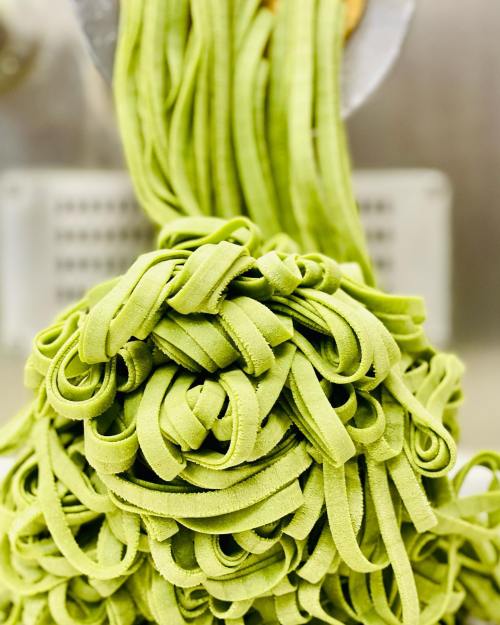 Fresh green pasta strands piled together, showcasing a vibrant color and smooth texture.