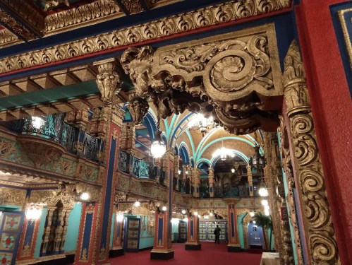 Ornate interior of a historic theater, featuring colorful walls, intricate carvings, and decorative lighting.