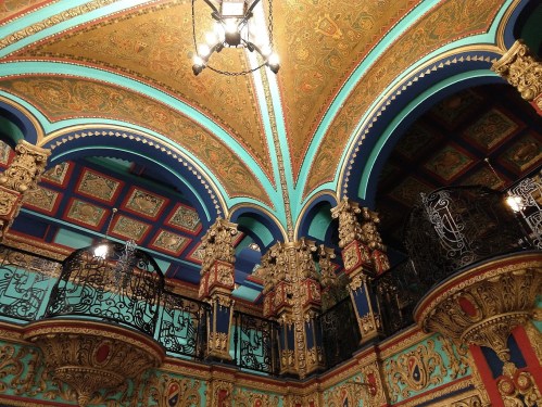 Ornate ceiling and colorful walls with intricate patterns and decorative columns in a historic building interior.