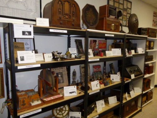 Display of vintage radios and communication devices on shelves, showcasing historical artifacts and information plaques.