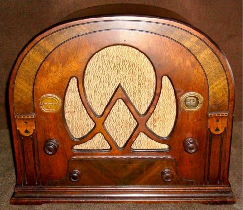 A vintage wooden radio with an ornate design and a woven speaker grille, showcasing classic craftsmanship.